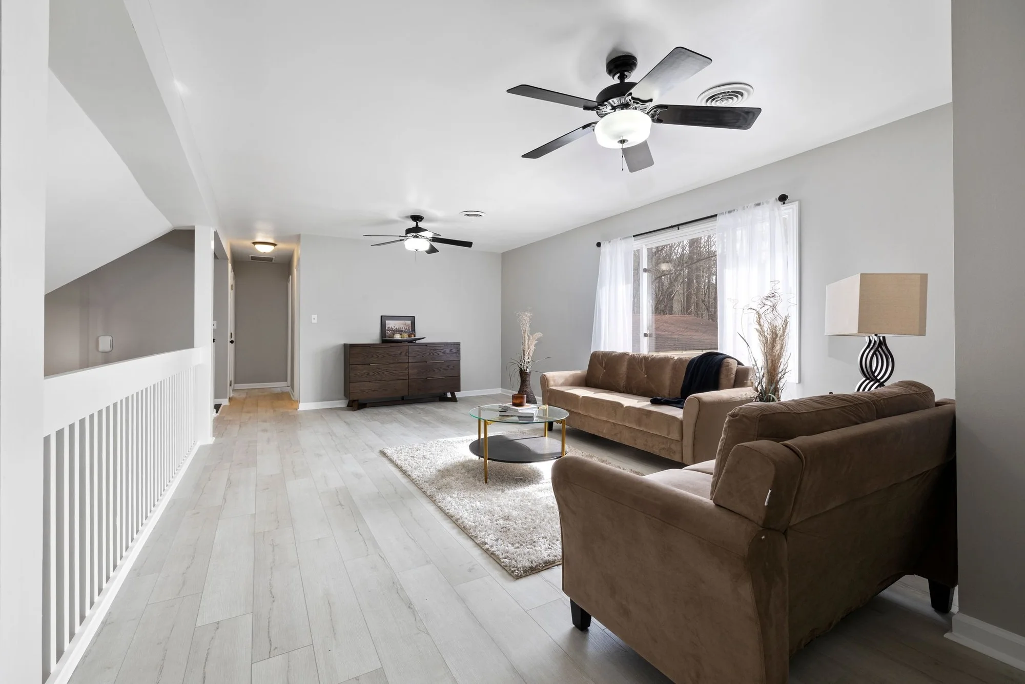 Warm, tidy living room with ceiling fans and a garden view